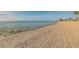 Serene beachfront view with calm waters, soft sand, and distant palm trees, inviting relaxation and tranquility at 4559 Mitcher Rd, New Port Richey, FL 34652