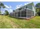 Large screened-in pool on the back of the house with a lush green lawn at 4559 Mitcher Rd, New Port Richey, FL 34652