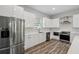 Modern kitchen with white cabinets, stainless steel appliances, and wood-look flooring at 4559 Mitcher Rd, New Port Richey, FL 34652