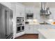 Close-up of the kitchen featuring stainless steel appliances, white cabinets, and a mosaic tile backsplash at 4824 Benito Ct, Bradenton, FL 34211