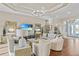 A great room featuring hardwood floors, tray ceilings, a modern chandelier, and views of the kitchen and outdoor spaces at 4824 Benito Ct, Bradenton, FL 34211