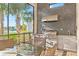 Outdoor kitchen on a covered patio, equipped with a grill, sink, and seating with lake views at 4824 Benito Ct, Bradenton, FL 34211