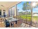 Screened-in patio with a dining table, offering picturesque views of the lake and manicured landscape at 4824 Benito Ct, Bradenton, FL 34211
