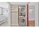 Laundry area with stacked washer and dryer, adjacent to a light-filled room with white floating shelves at 5912 N Lynn Ave, Tampa, FL 33604