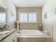 Relaxing bathroom featuring a large soaking tub, marble surround, and a window with blinds, creating a spa-like atmosphere at 6716 Frontier Ln, Tampa, FL 33625