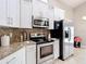 Bright kitchen featuring stainless steel appliances, granite countertops, and bright white cabinetry at 6716 Frontier Ln, Tampa, FL 33625