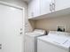 Bright laundry room with white washer and dryer and overhead cabinets, offering practical storage solutions at 6716 Frontier Ln, Tampa, FL 33625