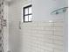 Updated bathroom with white subway tile, a shower niche and a modern glass shelf at 7049 Peninsular Dr, New Port Richey, FL 34652