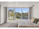Bedroom featuring neutral colored carpet, a ceiling fan and a large window with views of the surrounding trees and sky at 7049 Peninsular Dr, New Port Richey, FL 34652