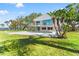 Beautiful backyard showcasing a waterfront home, expansive green lawn, mature tropical foliage, and pool at 7049 Peninsular Dr, New Port Richey, FL 34652