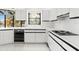 Modern kitchen with white cabinetry, black appliances and views of the water at 7049 Peninsular Dr, New Port Richey, FL 34652