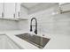 Close up on a kitchen sink with stainless steel basin and black faucet. Modern backsplash at 7804 N Whittier St, Tampa, FL 33617