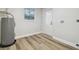 Utility room with water heater, door, and window, and light-colored wood-look flooring at 7804 N Whittier St, Tampa, FL 33617