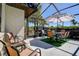 Charming screened patio features outdoor dining area with striped umbrella and manicured lawn at 10 Arbor Ln, Oldsmar, FL 34677