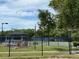 Well-maintained tennis courts surrounded by fencing, trees, and landscaping at 10 Arbor Ln, Oldsmar, FL 34677