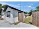 Side view of a single-story home with white stucco, black trim, a wooden privacy fence, and a concrete patio at 1138 Howard St, Clearwater, FL 33756