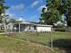 Single-story home with a fenced yard, lush green lawn, and mature trees under a partly cloudy sky at 12201 N. Blvd, Tampa, FL 33612