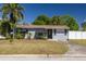 Cozy home featuring a well-kept lawn, palm trees, and a paved driveway, complemented by a white picket fence at 1541 68Th N Ave, St Petersburg, FL 33702