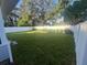 Manicured backyard features healthy green lawn, landscaping, and white vinyl fencing at 1574 Ewing Ave, Clearwater, FL 33756