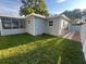 Exterior view of home featuring screened porch, manicured lawn, and fenced yard at 1574 Ewing Ave, Clearwater, FL 33756