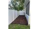 A brown mulch bed runs along the side of the home with a white vinyl fence at 1574 Ewing Ave, Clearwater, FL 33756