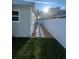 A paved walkway divides the side yard with grass and a white vinyl fence at 1574 Ewing Ave, Clearwater, FL 33756
