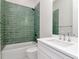 Bright bathroom features tub and shower with stunning green tile surround at 2050 Hawaii Ne Ave, St Petersburg, FL 33703