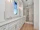 Bright bathroom with double sinks, white cabinets, and a tiled shower with glass door at 2050 Hawaii Ne Ave, St Petersburg, FL 33703