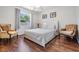 Bright bedroom with hardwood floors, ceiling fan, a large window and two decorative chairs at 2755 Merlin Way, Clearwater, FL 33761