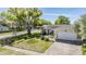 Single-story home featuring a manicured front yard with mature trees providing ample shade at 2755 Merlin Way, Clearwater, FL 33761