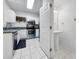 Functional kitchen adjacent to a bathroom with stainless steel appliances and white cabinets at 30132 Wellesley Way, Wesley Chapel, FL 33543