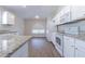 Well-lit kitchen featuring stainless steel appliances, white cabinets, granite countertops, and wood-look flooring at 3138 Clover Blossom Cir, Land O Lakes, FL 34638