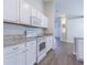 Well-equipped kitchen features modern appliances, granite counters, white cabinetry, and wood-look flooring at 3138 Clover Blossom Cir, Land O Lakes, FL 34638