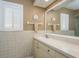 Bright bathroom featuring tiled walls, a vanity with a white countertop and a sun decoration above the towel rack at 3388 Tarpon Woods Blvd, Palm Harbor, FL 34685