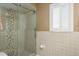Bathroom with a glass-enclosed shower with hexagon tile detail and a window with white shutters at 3388 Tarpon Woods Blvd, Palm Harbor, FL 34685