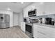 Bright kitchen featuring stainless appliances, gray countertops, white cabinets and wood-look flooring at 3808 97Th N Ave, Pinellas Park, FL 33782