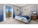 Bright bedroom featuring tray ceilings, plush carpet, and a sliding glass door leading to a private balcony with treeline view at 4600 Lagona Ln, Wesley Chapel, FL 33543