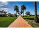 A scenic brick pathway lined with palm trees leads to a charming gazebo in a lush green park-like setting at 4801 Osprey S Dr # 508, St Petersburg, FL 33711