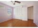 This bedroom features wood flooring, a ceiling fan, closet space, and a window that allows natural light at 5010 45Th N Ave, St Petersburg, FL 33709