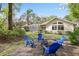 Spacious backyard featuring lush greenery, inviting blue chairs surrounding a fire pit, and the home's exterior at 6109 Kingbird Manor Dr, Lithia, FL 33547