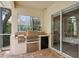 An outdoor kitchen with a grill, mini fridge, and a tile countertop sits on a patio with sliding glass doors at 6109 Kingbird Manor Dr, Lithia, FL 33547