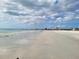 Expansive white sand beach meets the clear blue ocean under a partly cloudy sky, perfect for relaxation and recreation at 7300 Sun Island S Dr # 202, South Pasadena, FL 33707