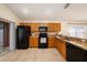 Well-lit kitchen with wooden cabinets, granite countertops, black appliances, and sliding glass door at 7924 Carriage Pointe Dr, Gibsonton, FL 33534