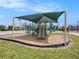Outdoor playground featuring climbing structures, slides, covered by a green awning, and surrounded by green grass at 7924 Carriage Pointe Dr, Gibsonton, FL 33534