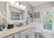 Bright bathroom with granite countertop, white cabinets, decorative mirror, and a window with plantation shutters at 1002 Romano Ne Ct, St Petersburg, FL 33702