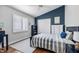 Comfortable bedroom features a blue accent wall, wood floors, white shutters, and a cozy bed at 1002 Romano Ne Ct, St Petersburg, FL 33702
