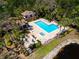 Aerial view of the community pool, showcasing lounge chairs, tables, umbrellas and lush landscaping at 1002 Romano Ne Ct, St Petersburg, FL 33702