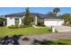Inviting home exterior featuring a manicured lawn, a dark roof, a three car garage, and lush landscaping at 1002 Romano Ne Ct, St Petersburg, FL 33702
