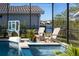 Outdoor pool area with tiled deck, lounge chairs, water feature, and a view of the lake at 1002 Romano Ne Ct, St Petersburg, FL 33702