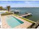 An inground pool with a dock and a boat parked near a beautifully landscaped yard with palm trees on the water at 109 Punta Vista Dr, St Pete Beach, FL 33706